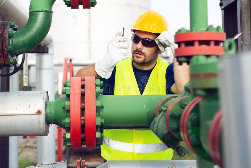 Ingegnere che lavora dentro la raffineria del gas e del petrolio fotografie stock Ingegnere che lavora dentro la raffineria del gas e del petrolio fotografie stock
