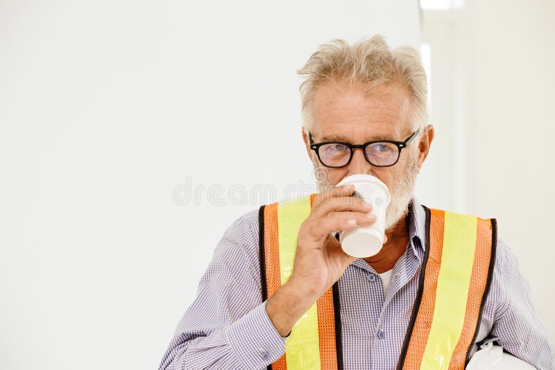 Ingegnere o caposquadra di alto livello che beve caffè caldo immagine stock libera da diritti Ingegnere o caposquadra di alto livello che beve caffè caldo immagine stock libera da diritti