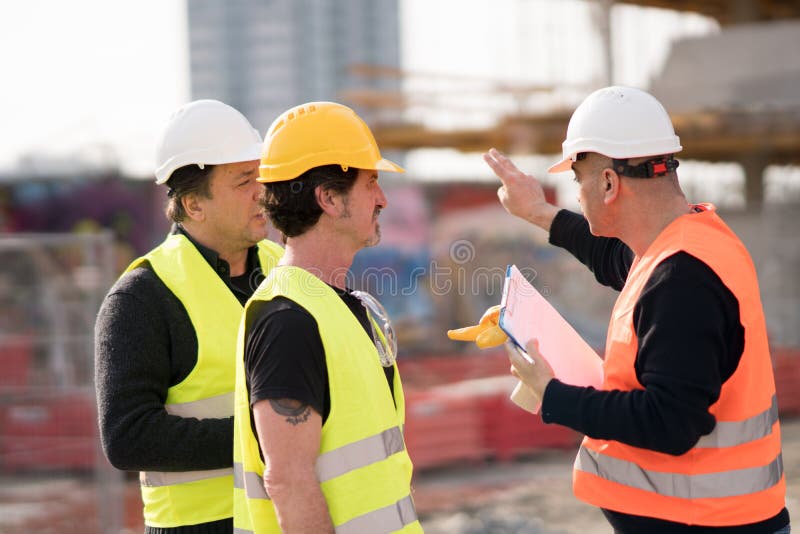 Ingegneri e muratori sul lavoro fotografia stock Ingegneri e muratori sul lavoro fotografia stock