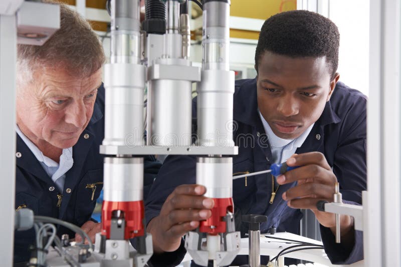 Ingeniero And Apprentice Working en la máquina en fábrica imágenes de archivo libres de regalías