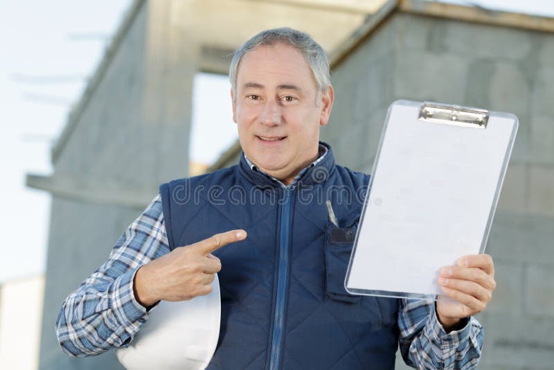 Ingeniero de alto rango sujetando el portapapeles y señalando fotografía de archivo libre de regalías