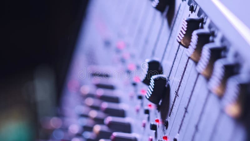Ingeniero de sonido vertical mueve los atenuadores hacia arriba y hacia abajo en el mezclador de audio con luz de neón almacen de metraje de vídeo