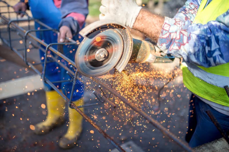 Ingeniero industrial que trabaja en cortar un metal y una barra de acero con la amoladora de ángulo fotografía de archivo Ingeniero industrial que trabaja en cortar un metal y una barra de acero con la amoladora de ángulo fotografía de archivo
