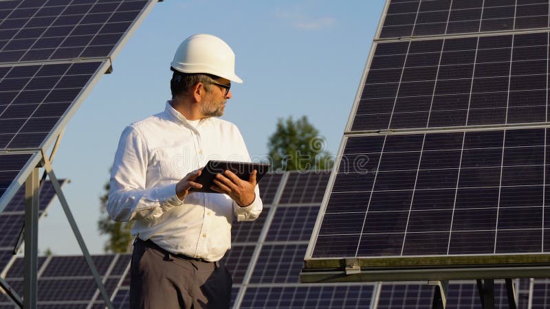 Ingeniero inspector jefe que sostiene tableta digital que trabaja en la granja de energía de paneles solares