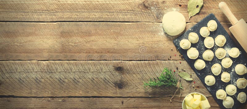 Ingredienser för framställning av pelmenien, ravioli, klimpar - deg, rosmarin, kavel, kanfastråd, smör, lagerblad överkant royaltyfri fotografi