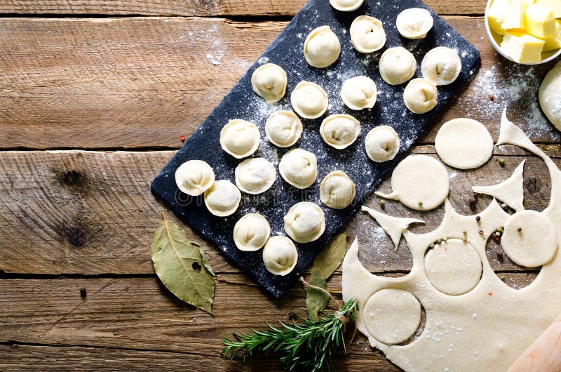 Ingredienser för framställning av pelmenien, ravioli, klimpar - deg, rosmarin, kavel, kanfastråd, smör, lagerblad överkant arkivbilder