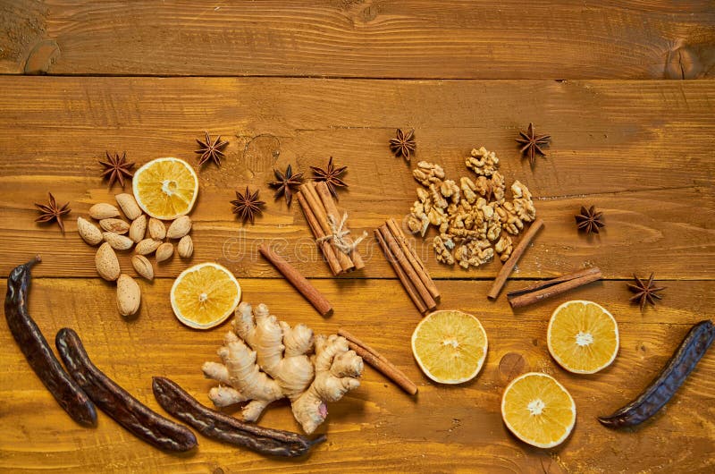 Ingredienser för funderat vin: torkade frukter, apelsin, carob, ingefära, pinnar av kanel, anisstjärnor, muttrar på träbrun bakgr royaltyfria bilder Ingredienser för funderat vin: torkade frukter, apelsin, carob, ingefära, pinnar av kanel, anisstjärnor, muttrar på träbrun bakgr royaltyfria bilder