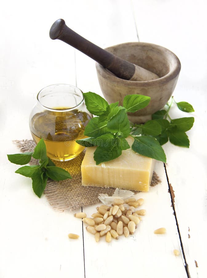 Italian pesto ingredients: parmegiano regiano, basil, olive oil and pine nuts with mortar and pestle. Italian pesto ingredients: parmegiano regiano, basil, olive oil and pine nuts with mortar and pestle
