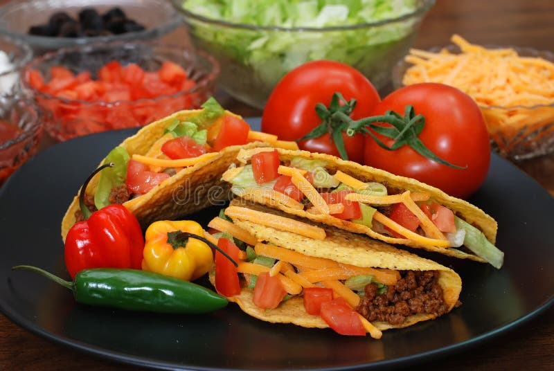 Prepared tacos with tomatoes, habanero and serrano peppers on plate. Ingredients in background. Prepared tacos with tomatoes, habanero and serrano peppers on plate. Ingredients in background.