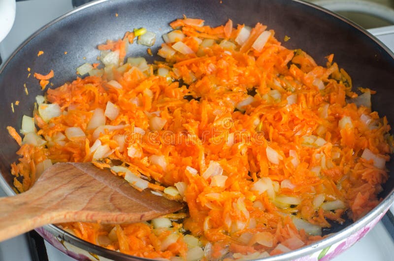 Ingrediente cocinado de la sopa Cebollas tajadas salteadas y zanahorias ralladas para la sopa en un sartén Vehículos fritos imágenes de archivo libres de regalías Ingrediente cocinado de la sopa Cebollas tajadas salteadas y zanahorias ralladas para la sopa en un sartén Vehículos fritos imágenes de archivo libres de regalías