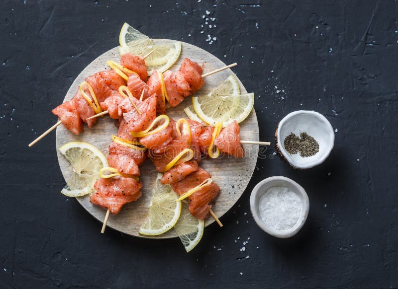 Ingredientes crus para cozinhar os espetos salmon na grade Espetos salmon crus, limão, pimenta, sal do mar em uma placa de corte imagens de stock royalty free Ingredientes crus para cozinhar os espetos salmon na grade Espetos salmon crus, limão, pimenta, sal do mar em uma placa de corte imagens de stock royalty free