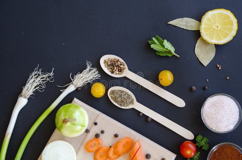 Ingredientes deliciosos frescos para o cozimento saudável ou salada que faz no fundo do preto escuro e na placa de corte de madei foto de stock royalty free Ingredientes deliciosos frescos para o cozimento saudável ou salada que faz no fundo do preto escuro e na placa de corte de madei foto de stock royalty free