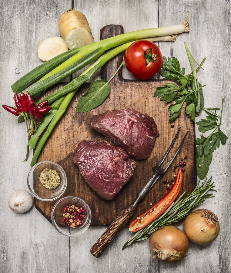 Ingredientes para cozinhar bifes da carne com vegetais do outono e temperos na placa de corte de madeira na parte traseira brilha imagens de stock royalty free Ingredientes para cozinhar bifes da carne com vegetais do outono e temperos na placa de corte de madeira na parte traseira brilha imagens de stock royalty free