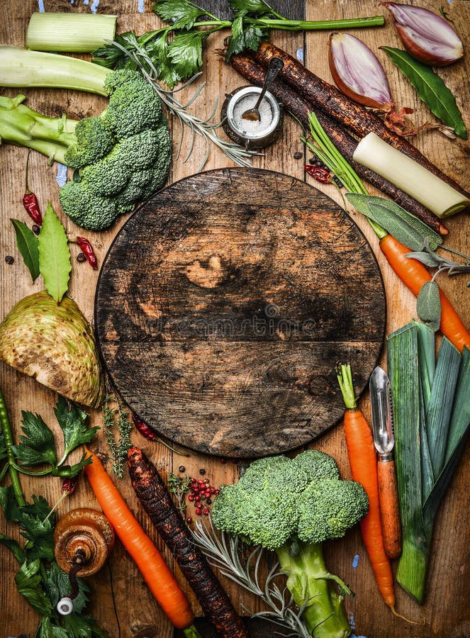 Ingredienti organici freschi delle verdure per minestra o brodo intorno al tagliere in bianco rustico rotondo, vista superiore