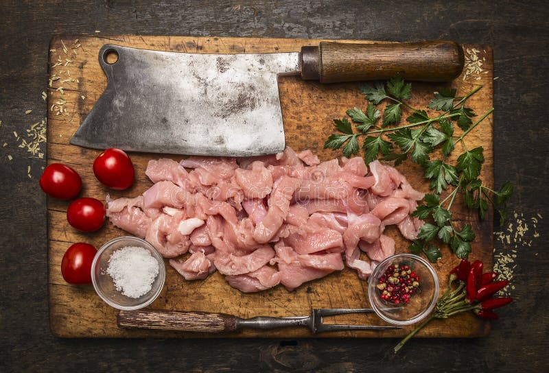 Ingredients for cooking a turkey,meat cleaver ,meat fork, salt ,pepper on a wooden cutting board on rustic wooden background top v