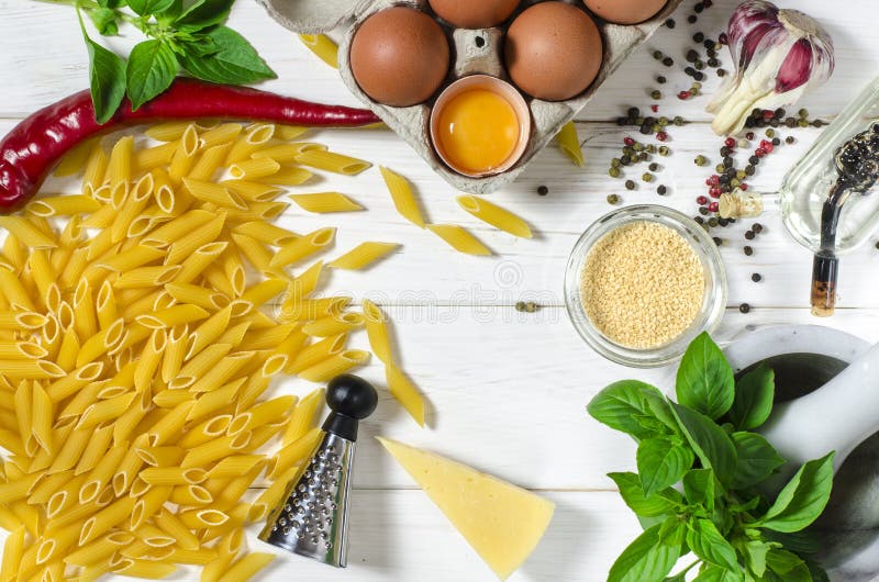 Penne Pasta, green basil, parmesan, sesame, garlic, chilli, eggs lie on a white tree table