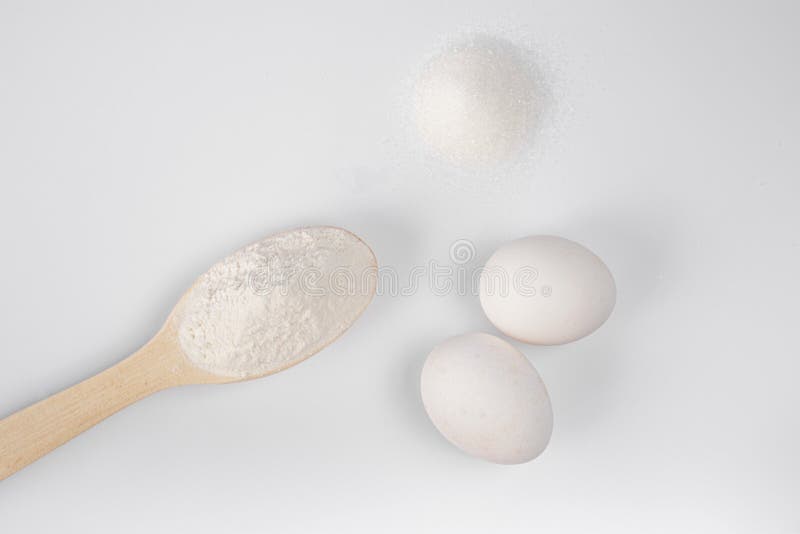 Ingredients for making pasta, pizza, cake, cookies. flour in a wooden spoon, sugar, eggs on a white background. products for cooki