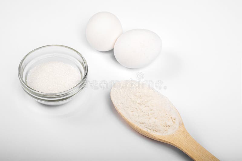Ingredients for making pasta, pizza, cake, cookies. flour in a wooden spoon, sugar, eggs on a white background. products for cooki