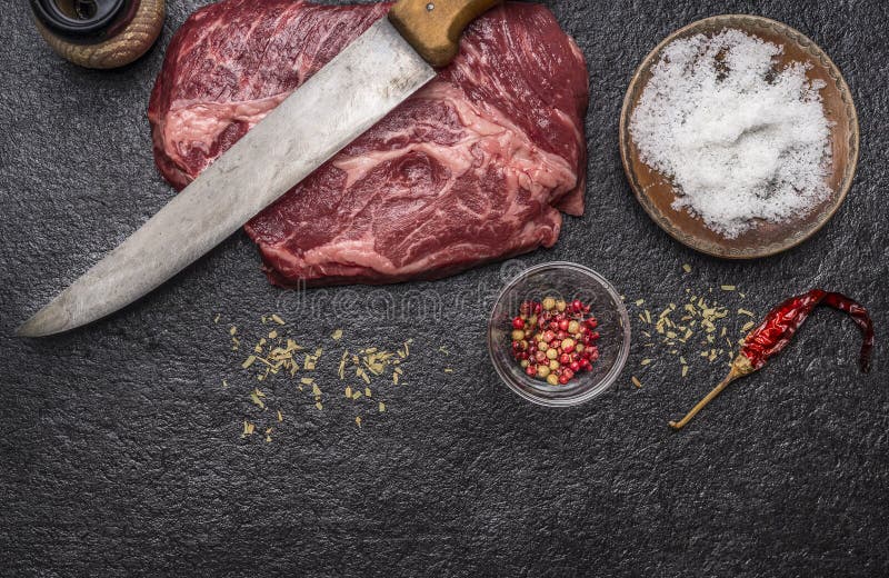 Ingrediënten voor het koken van ruw rundvleeslapje vlees met zout en peper donkere rustieke van de achtergrond voorsnijmespepermo stock afbeeldingen Ingrediënten voor het koken van ruw rundvleeslapje vlees met zout en peper donkere rustieke van de achtergrond voorsnijmespepermo stock afbeeldingen