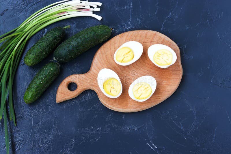 Ingrédients pour la salade : des oeufs à la coque, les concombres et les oignons verts sont situés sur un fond foncé photos stock Ingrédients pour la salade : des oeufs à la coque, les concombres et les oignons verts sont situés sur un fond foncé photos stock