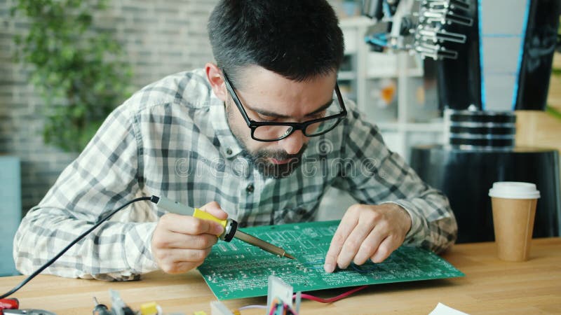 Ingénieur en microélectronique réparant le microcircuit pour les robots travaillant au bureau