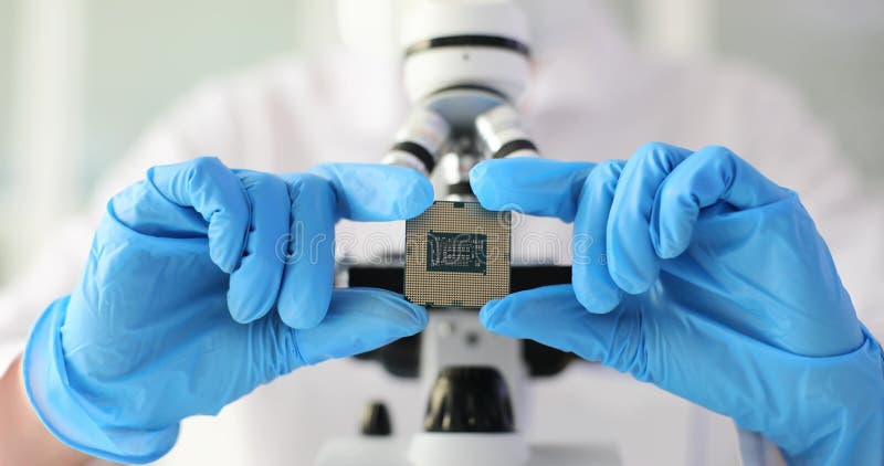 Ingénieur électronique en gant tient microcircuit sur fond de microscope
