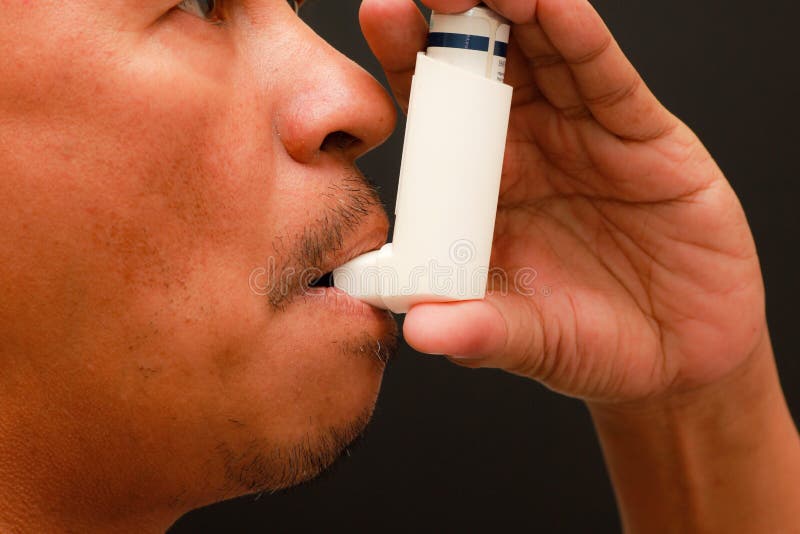 A man is using an inhaler to relieve himself of an asthma attack. A man is using an inhaler to relieve himself of an asthma attack.