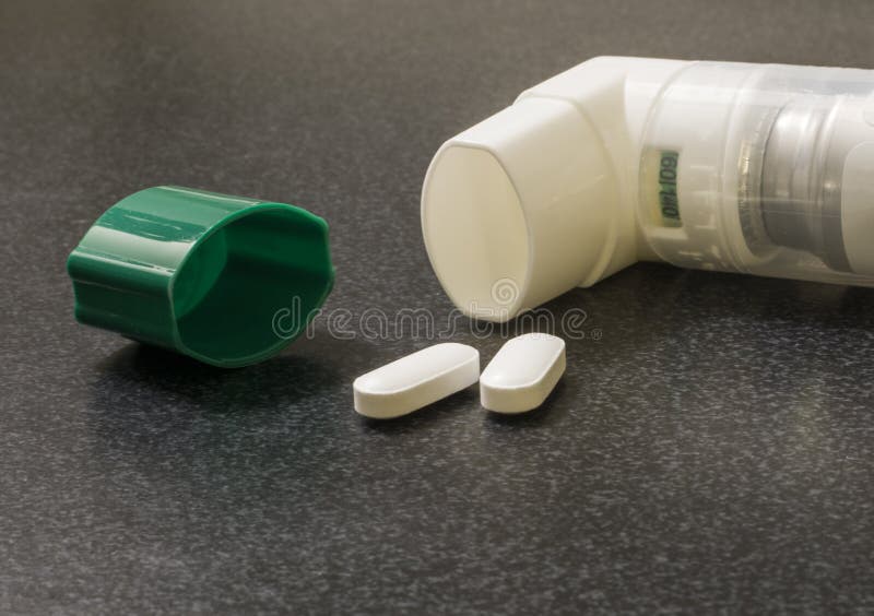 Inhalator z dwa białymi pigułkami i zielona nakrętka na medycznej powierzchni fotografia stock Inhalator z dwa białymi pigułkami i zielona nakrętka na medycznej powierzchni fotografia stock