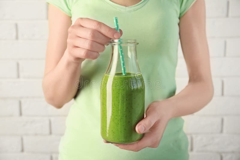 Innehavflaska för ung kvinna av den nya kiwiyoghurtsmoothien arkivbild Innehavflaska för ung kvinna av den nya kiwiyoghurtsmoothien arkivbild
