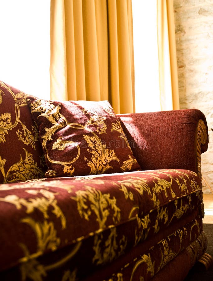 An interior of a room with a beautiful burgundy and gold sofa. An interior of a room with a beautiful burgundy and gold sofa.