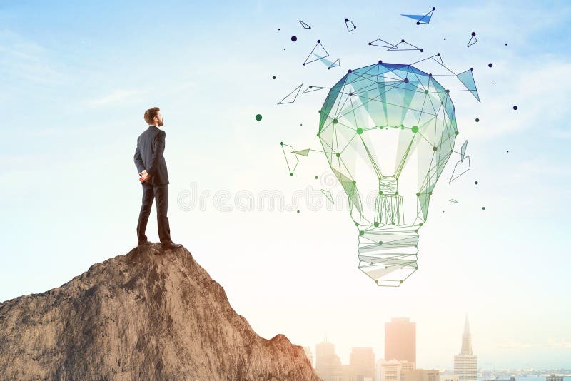 Back view of businessman on mountain top looking at abstract polygonal lamp. City and bright sky background. Innovation and idea concept