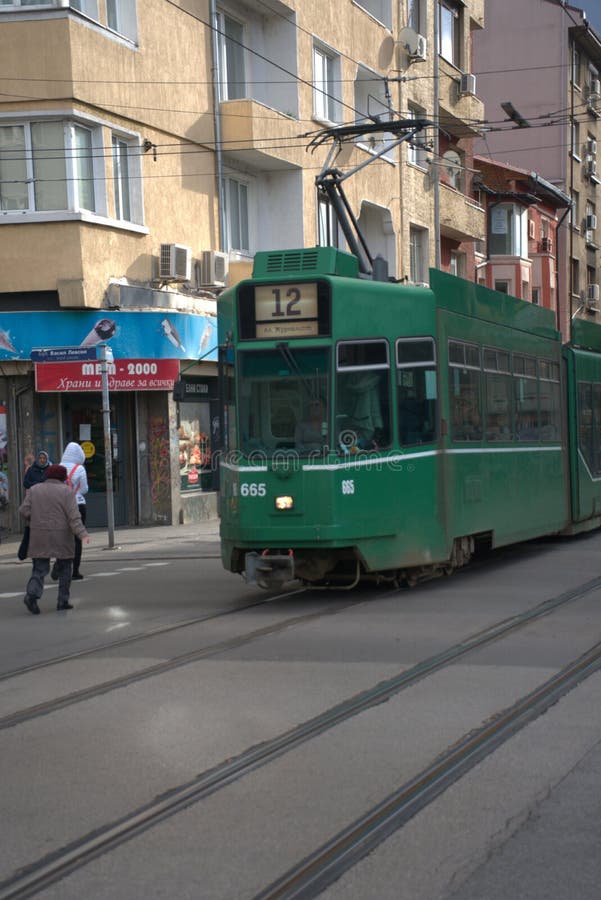 Inquadratura verticale di un tram che attraversa una strada stretta con edifici nel centro della strada immagini stock libere da diritti