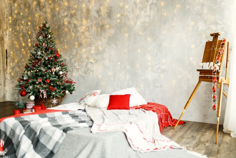 Inre rum som dekoreras i julstil. Sovrummet som dekoreras av jul Hemtrevlig ljus inre: pläd och träsäng I rummet finns det ettträd för ` s för nytt år som dekoreras med leksaker och girlander