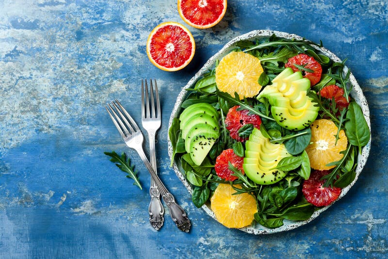 Citrus salad with mixed greens and blood orange. Vegan, vegetarian, clean eating, dieting, food concept. Blue stone background. Citrus salad with mixed greens and blood orange. Vegan, vegetarian, clean eating, dieting, food concept. Blue stone background