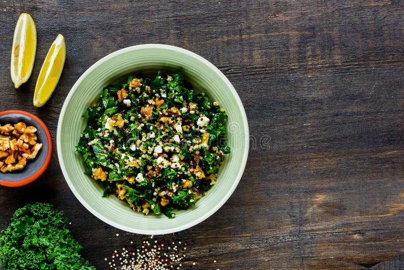 Close up of detox salad bowl. Healthy raw kale and quinoa salad with feta cheese and walnut on wooden background. Top view. Flat lay. Clean eating, dieting, vegetarian food concept. Close up of detox salad bowl. Healthy raw kale and quinoa salad with feta cheese and walnut on wooden background. Top view. Flat lay. Clean eating, dieting, vegetarian food concept