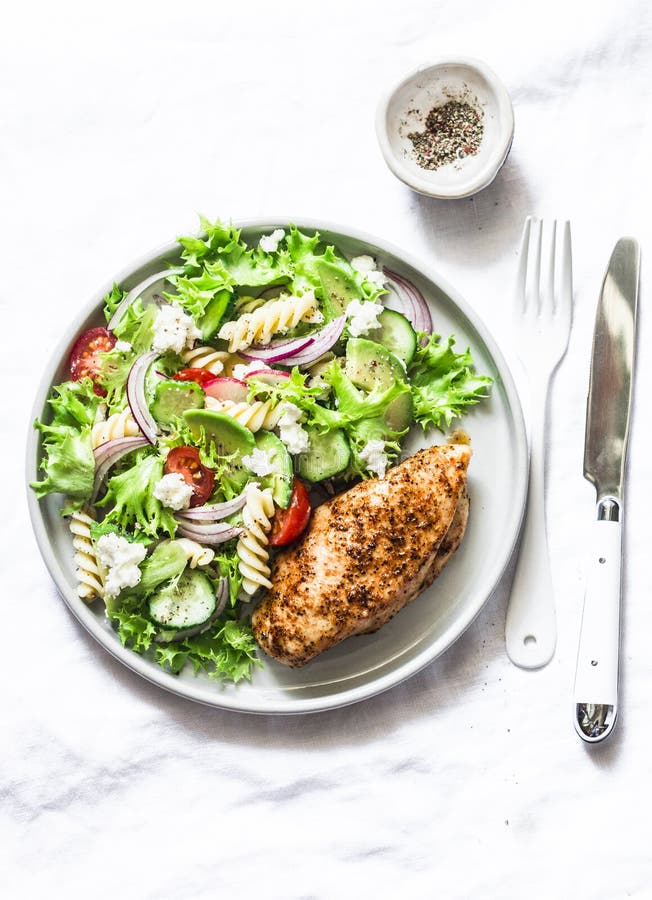 Insalata di pasta Mediterranea dell'avocado e petto di pollo al forno - pranzo equilibrato sano su un fondo leggero, vista superi fotografie stock Insalata di pasta Mediterranea dell'avocado e petto di pollo al forno - pranzo equilibrato sano su un fondo leggero, vista superi fotografie stock