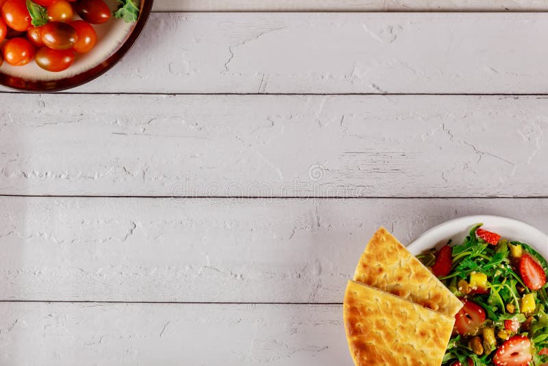 Insalata di rucola fresca con fragole, mango, pistacchi e pane di pita immagine stock libera da diritti Insalata di rucola fresca con fragole, mango, pistacchi e pane di pita immagine stock libera da diritti