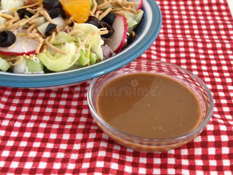 Insalata e vestirsi sugli assegni rossi immagine stock Insalata e vestirsi sugli assegni rossi immagine stock