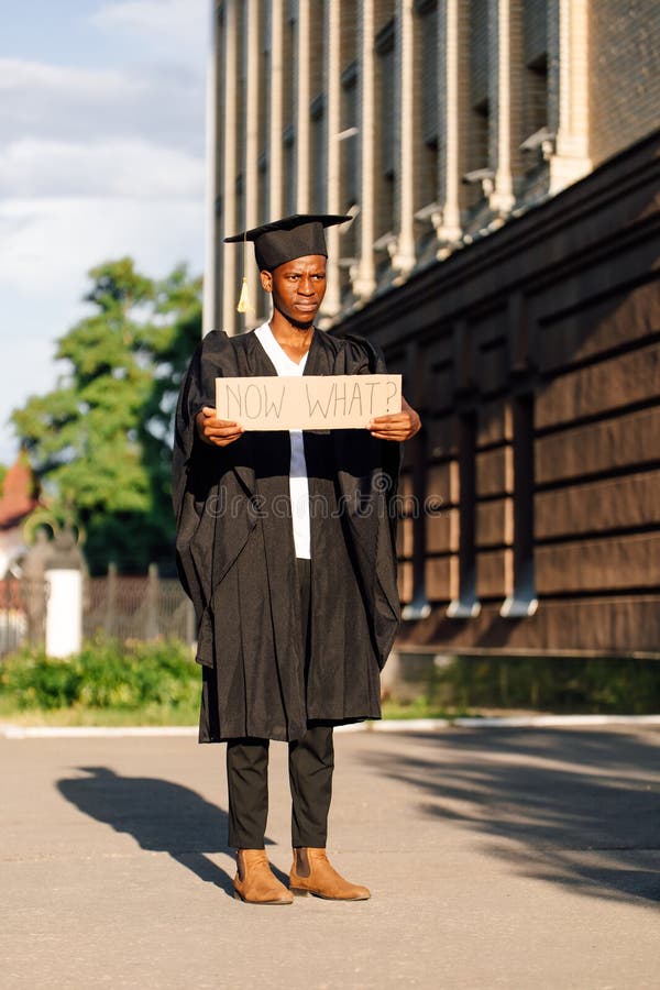 Insatisfecho afroamericano parado con un cartel de cartón en la calle en un día soleado buscando trabajo. universidad o