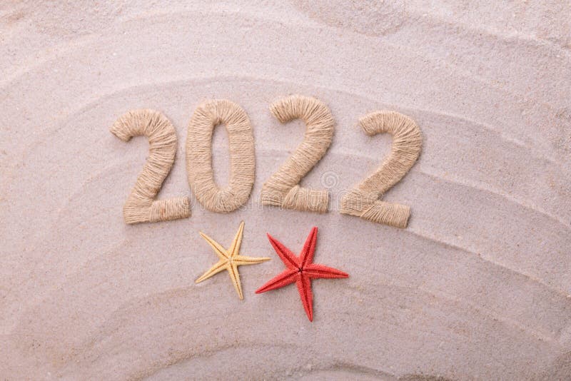 Inscription 2022 made of twine on background of sea sand stock photography