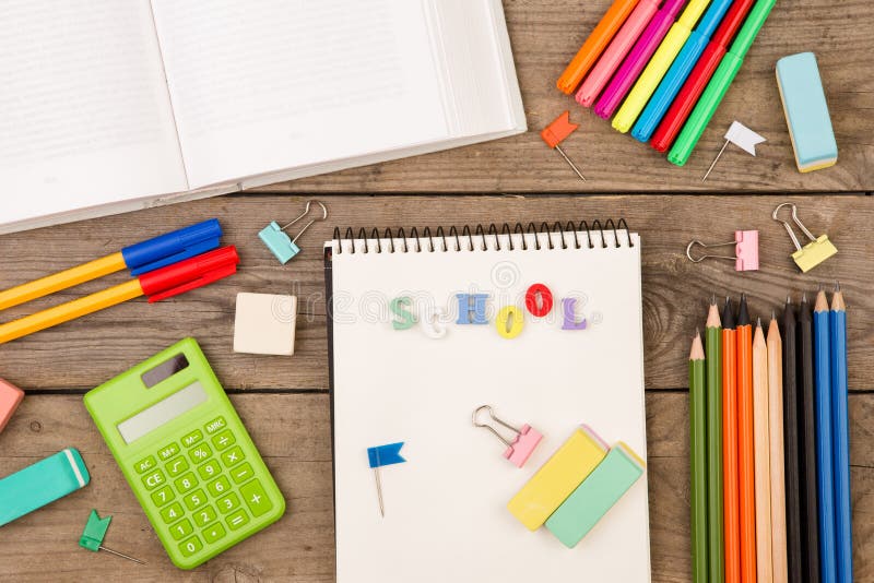 inscription of & x22;school& x22;, book, calculator, notepad and other stationery on brown wooden table