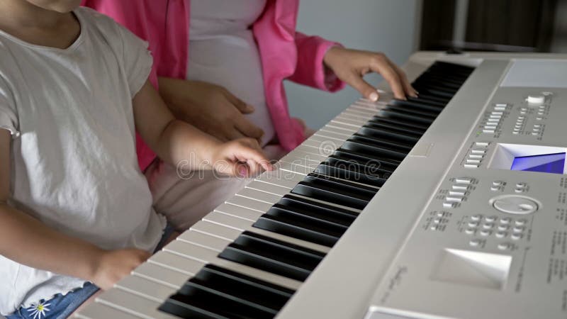 Insegnante di musica privata che dà lezioni di pianoforte a una bambina. chiudere le mani.