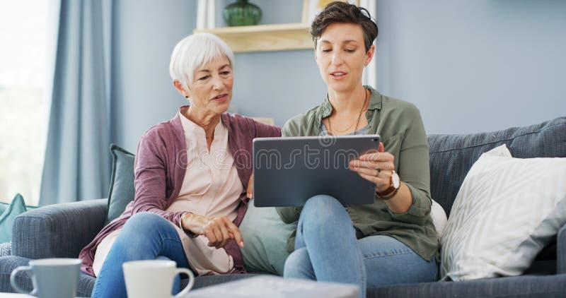 Insegnante in tavoletta e donna con madre anziana sul divano per chiacchierare o per la messa in rete. Tecnologia digitale fotografie stock libere da diritti