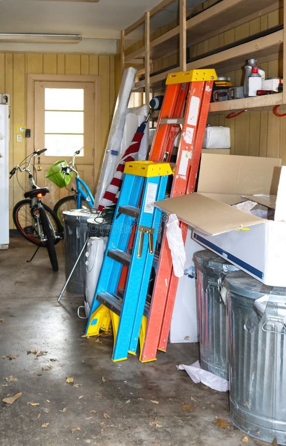 Insida av det smutsiga garaget med cyklar och stegar och amerikanska flaggan och askar och mer - selektiv fokus royaltyfria bilder Insida av det smutsiga garaget med cyklar och stegar och amerikanska flaggan och askar och mer - selektiv fokus royaltyfria bilder