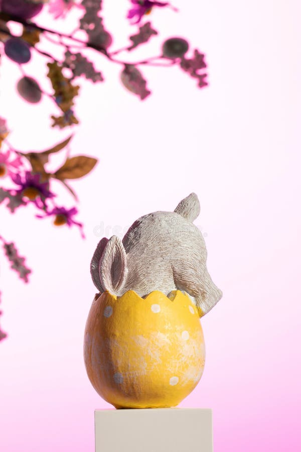 Inside the bright yellow Easter egg, a plush rabbit nestles comfortably, creating a whimsical still life. An Easter card stock image