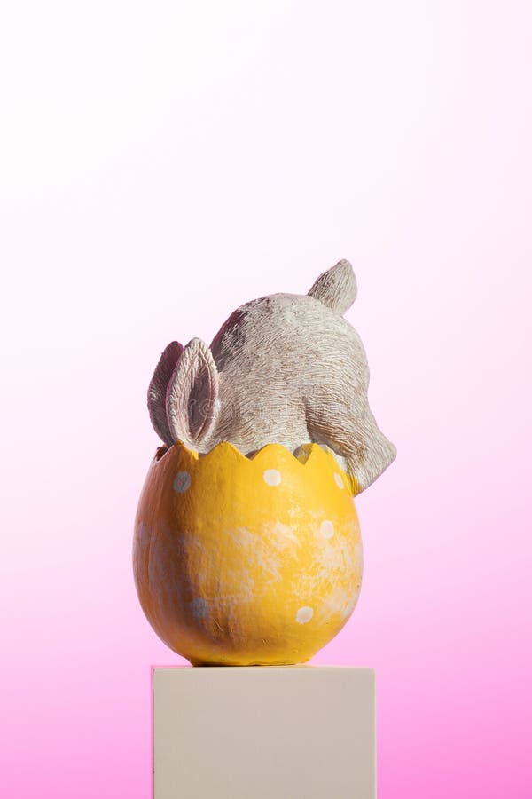 Inside the bright yellow Easter egg, a plush rabbit nestles comfortably, creating a whimsical still life. An Easter card stock image