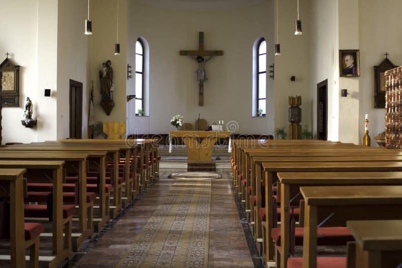 Inside of a large, traditional catholic church with pews and cross visible. Inside of a large, traditional catholic church with pews and cross visible.