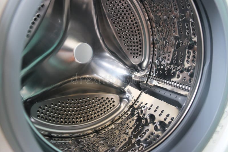 View of a modern front-loading washing machine drum, with clean, shiny stainless steel surface. The appliance represents household chores, laundry hygiene, and modern home technology. Metal steel drum stock images, royalty-free photos and pictures