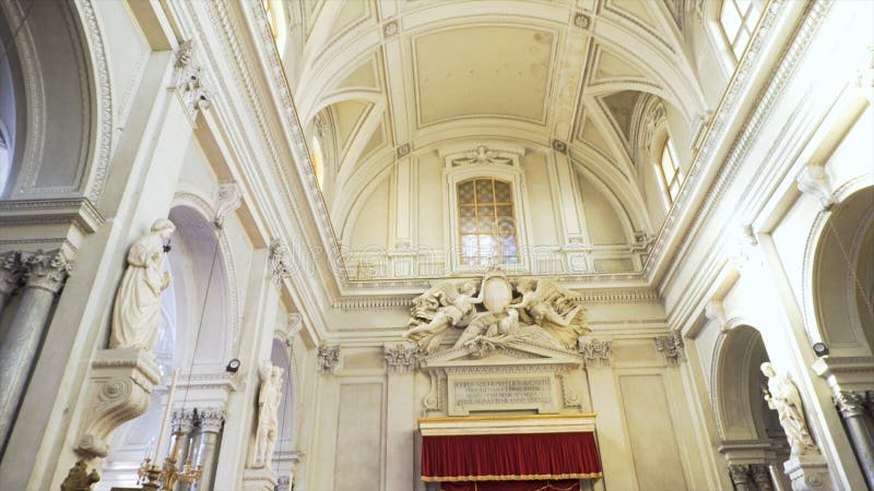 Inside of a large, beautiful church with arches and statues near light walls, religion concept. Interior of the cathedral with the statues of angels and saints, view to the ceiling and walls. Inside of a large, beautiful church with arches and statues near light walls, religion concept. Interior of the cathedral with the statues of angels and saints, view to the ceiling and walls.