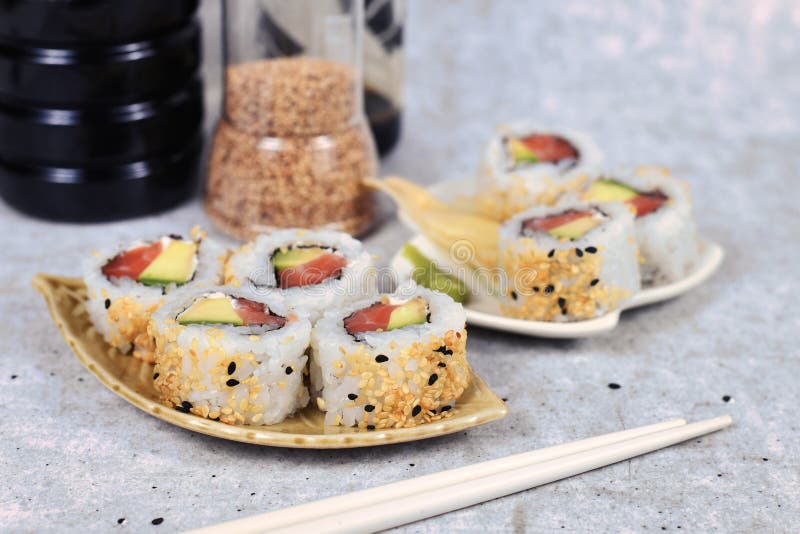 Inside out California roll sushi filed raw salmon fish, avocado, cream cheese and topped with sesame